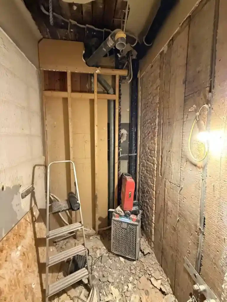 Frilagda rör, reglar och väggkonstruktion under badrumsrenovering på Valhallavägen.