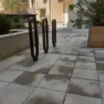 Gångyta med grå markplattor och svarta cykelställ på BRF Kastanjens renoverade innergård på Södermalm i Stockholm.