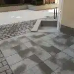 Stenläggning med markplattor och gatsten intill en entrétrappa på BRF Kastanjens innergård på Södermalm i Stockholm.