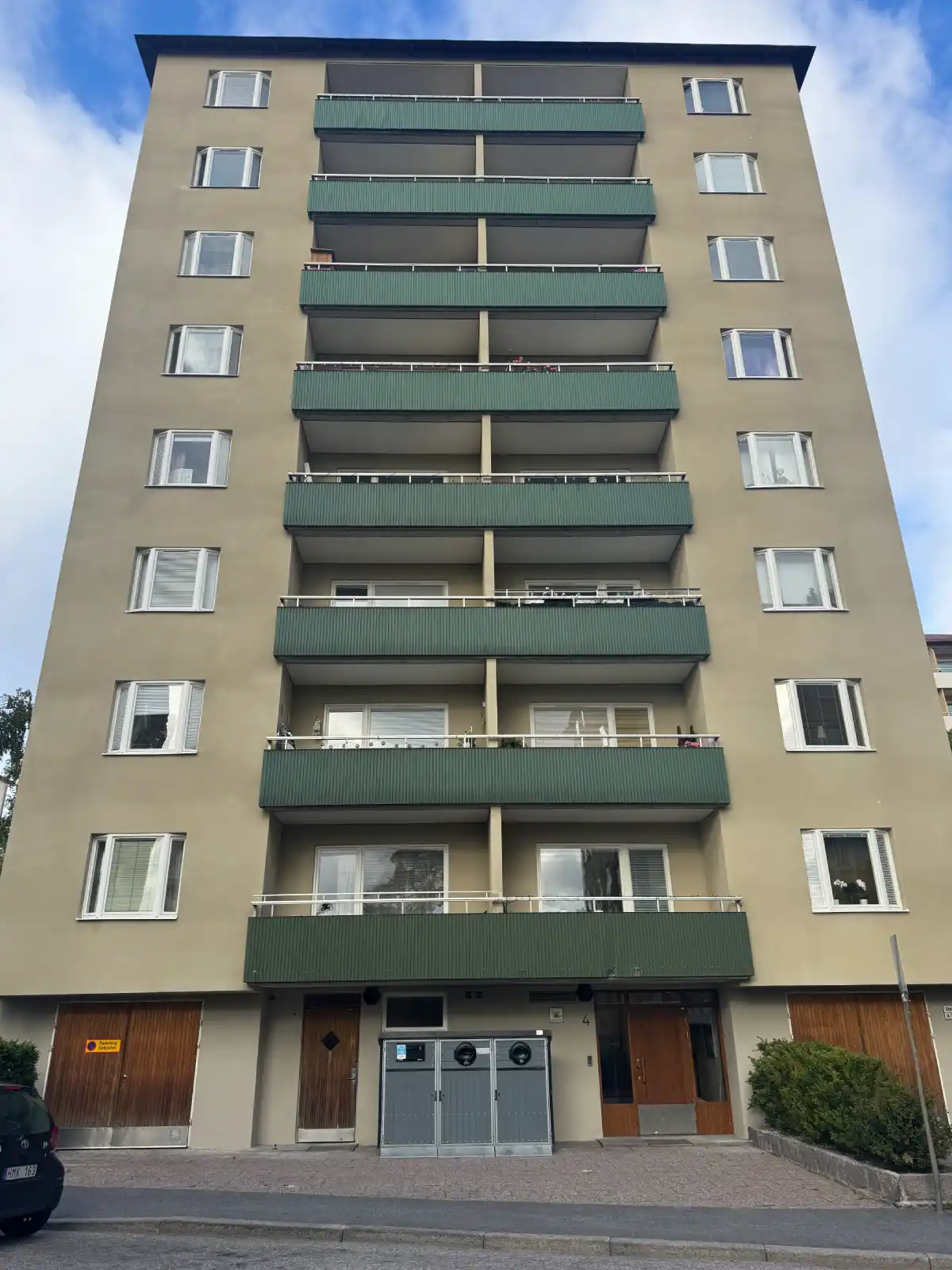Renoverad putsfasad med gröna balkonger och entré på Steningevägen 4 i Årsta, sedd från gatan.